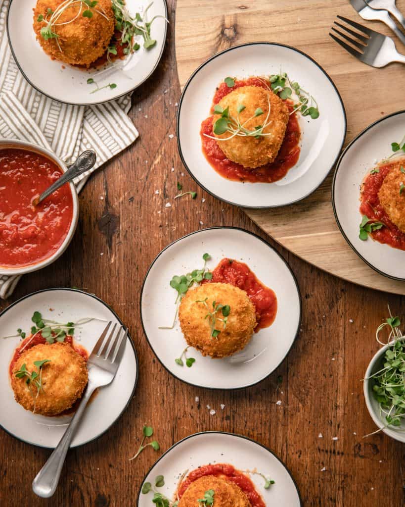 overhead view of small plates with crispy fried mashed potato balls with marinara sauce