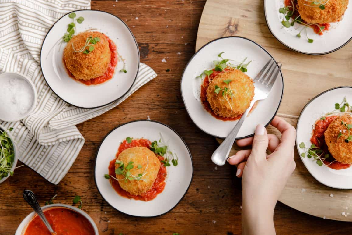 overhead view of small plates with crispy fried mashed potato balls with marinara sauce