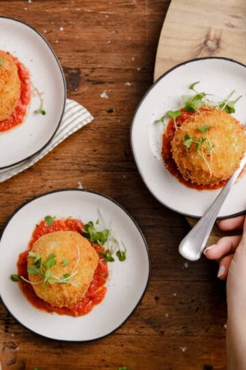 overhead view of small plates with crispy fried mashed potato balls with marinara sauce