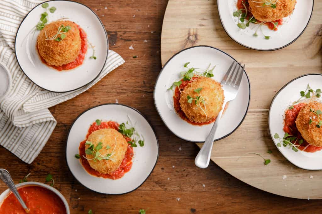 overhead view of small plates with crispy fried mashed potato balls with marinara sauce