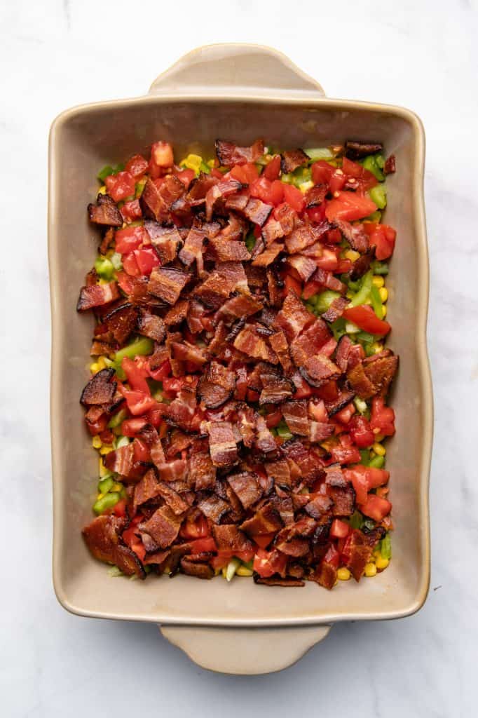 Corn and peppers and tomatoes and bacon in a casserole dish