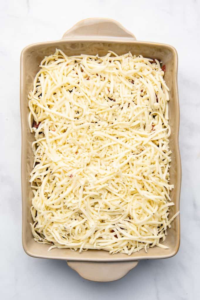 A casserole dish topped with cheese prior to baking