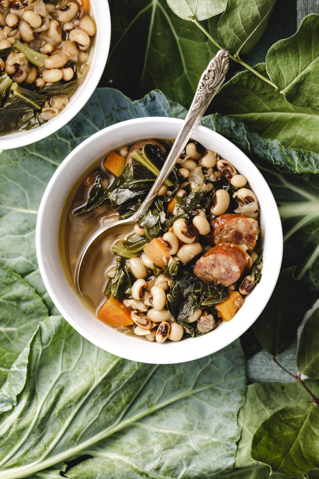 Black Eyed Pea Soup in a white bowl on a bed of collard greens