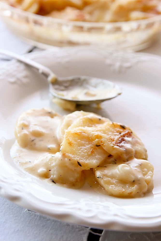 a white plate with scalloped potatoes and a serving spoon