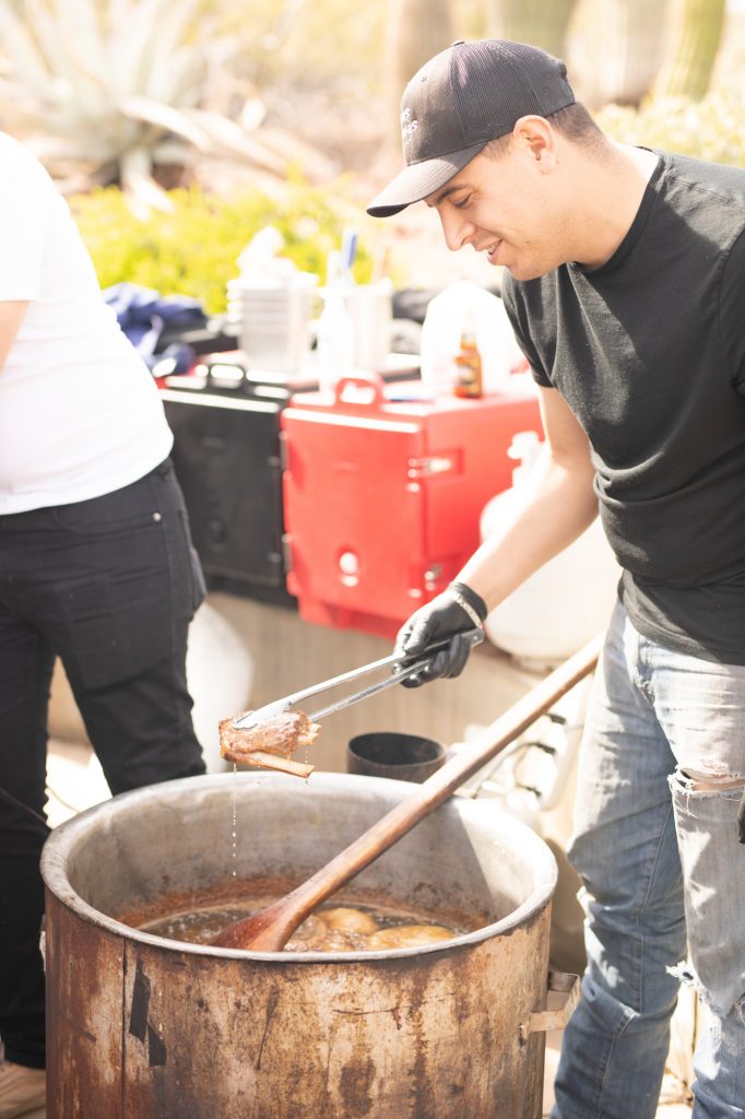 Chef pulling a piece of meat from a large pot
