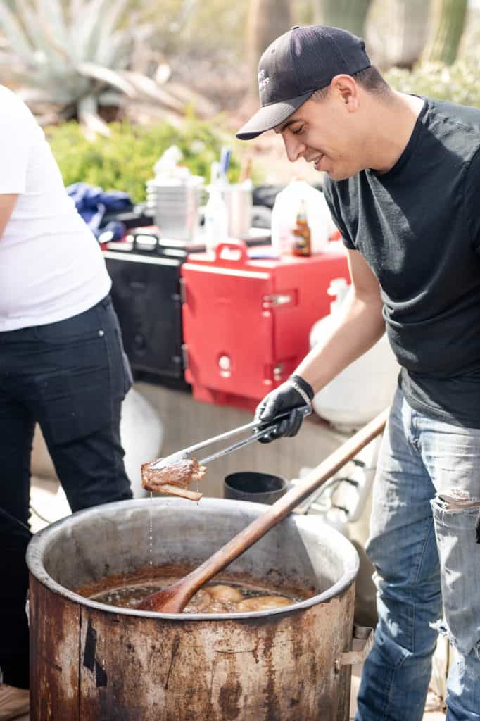 Chef pulling a piece of meat from a large pot