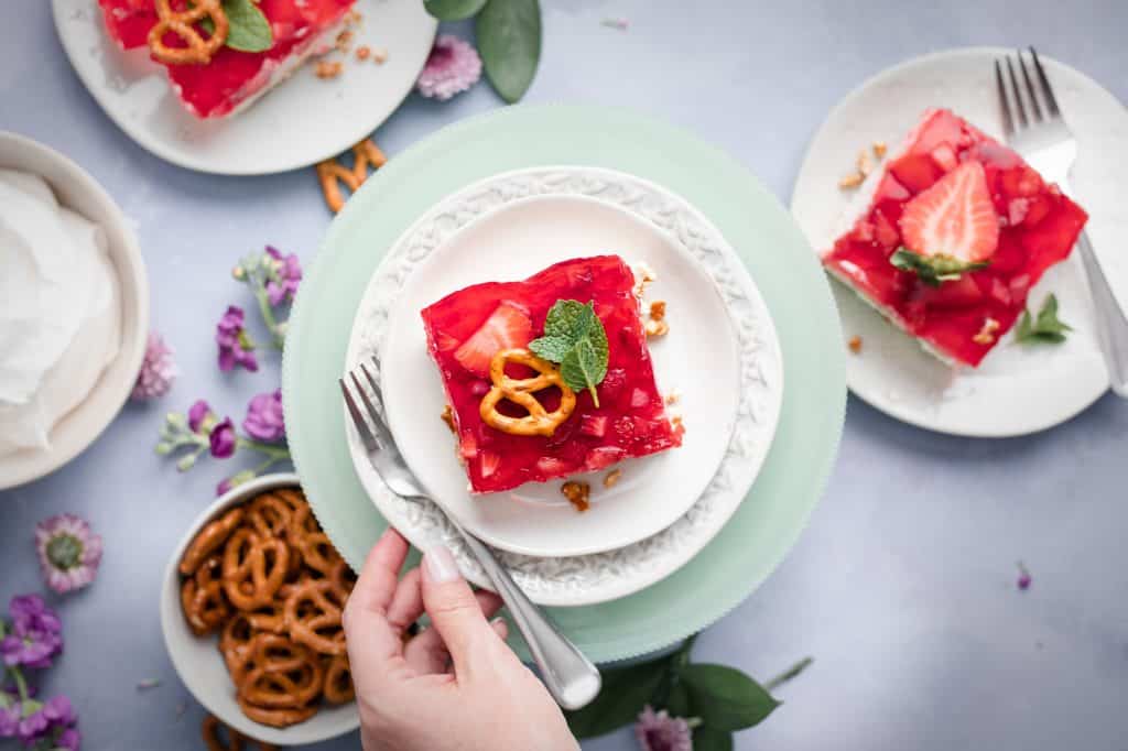 a plate with a dessert topped with strawberry jello and garnished with a pretzel