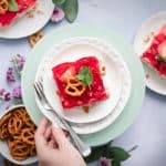 a plate with a dessert topped with strawberry jello and garnished with a pretzel