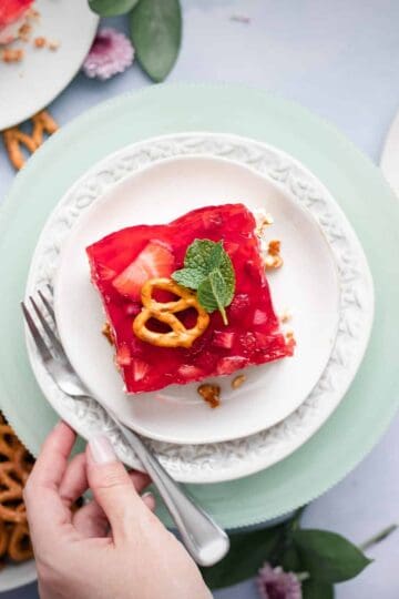 a plate with a dessert topped with strawberry jello and garnished with a pretzel