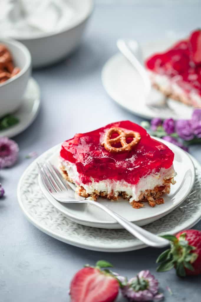 a plate with a dessert topped with strawberry jello and garnished with a pretzel