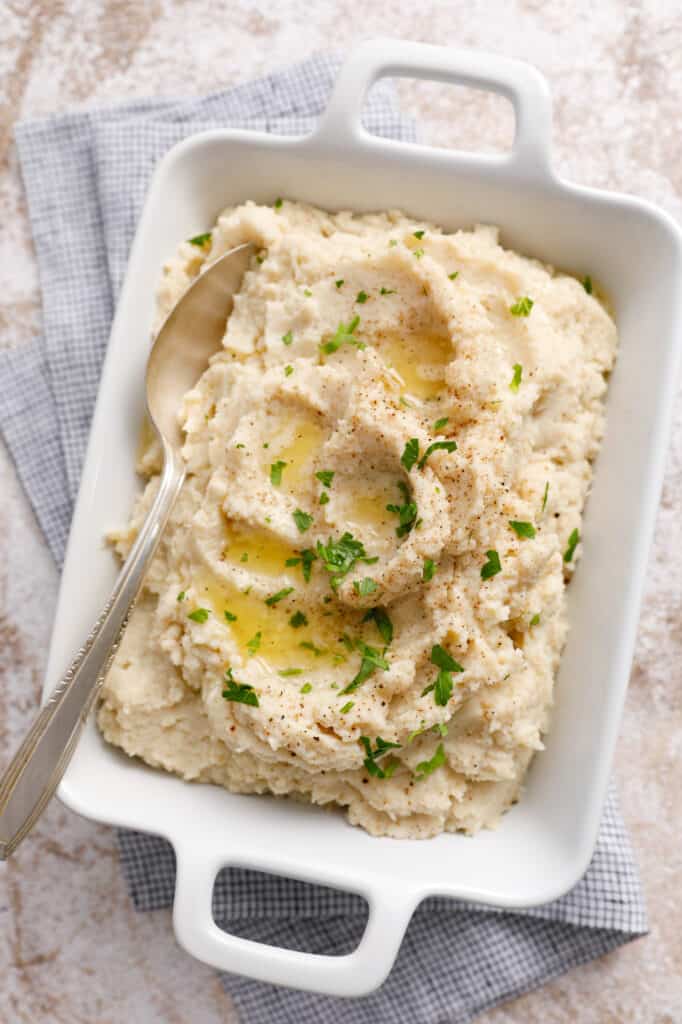 overhead view of a dish full of mashed cauliflower with pools of butter