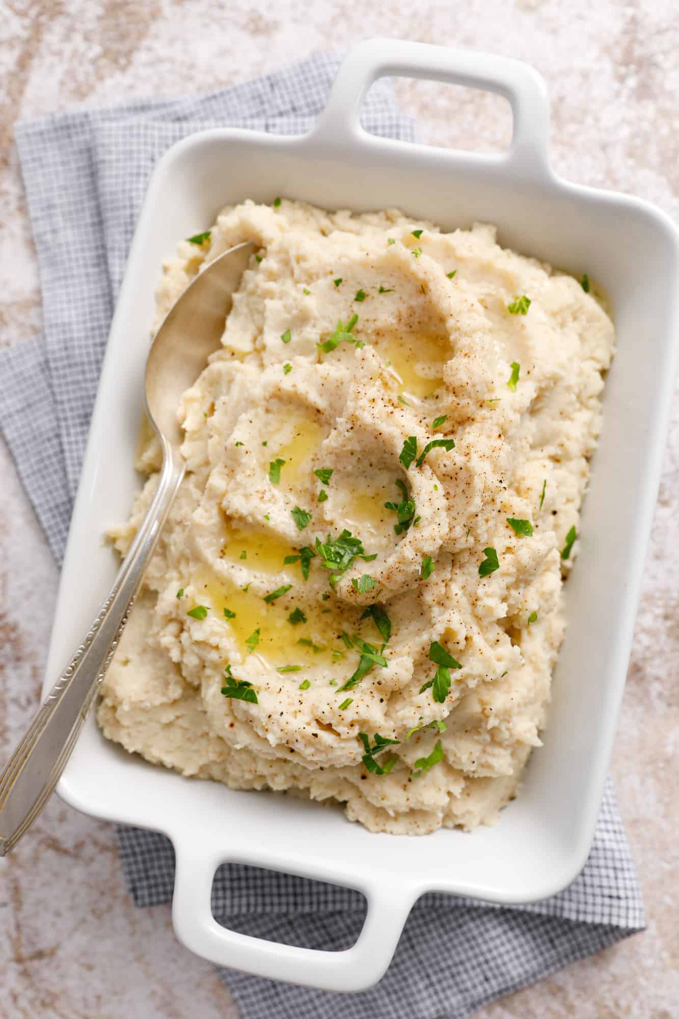 overhead view of a dish full of mashed cauliflower with pools of butter