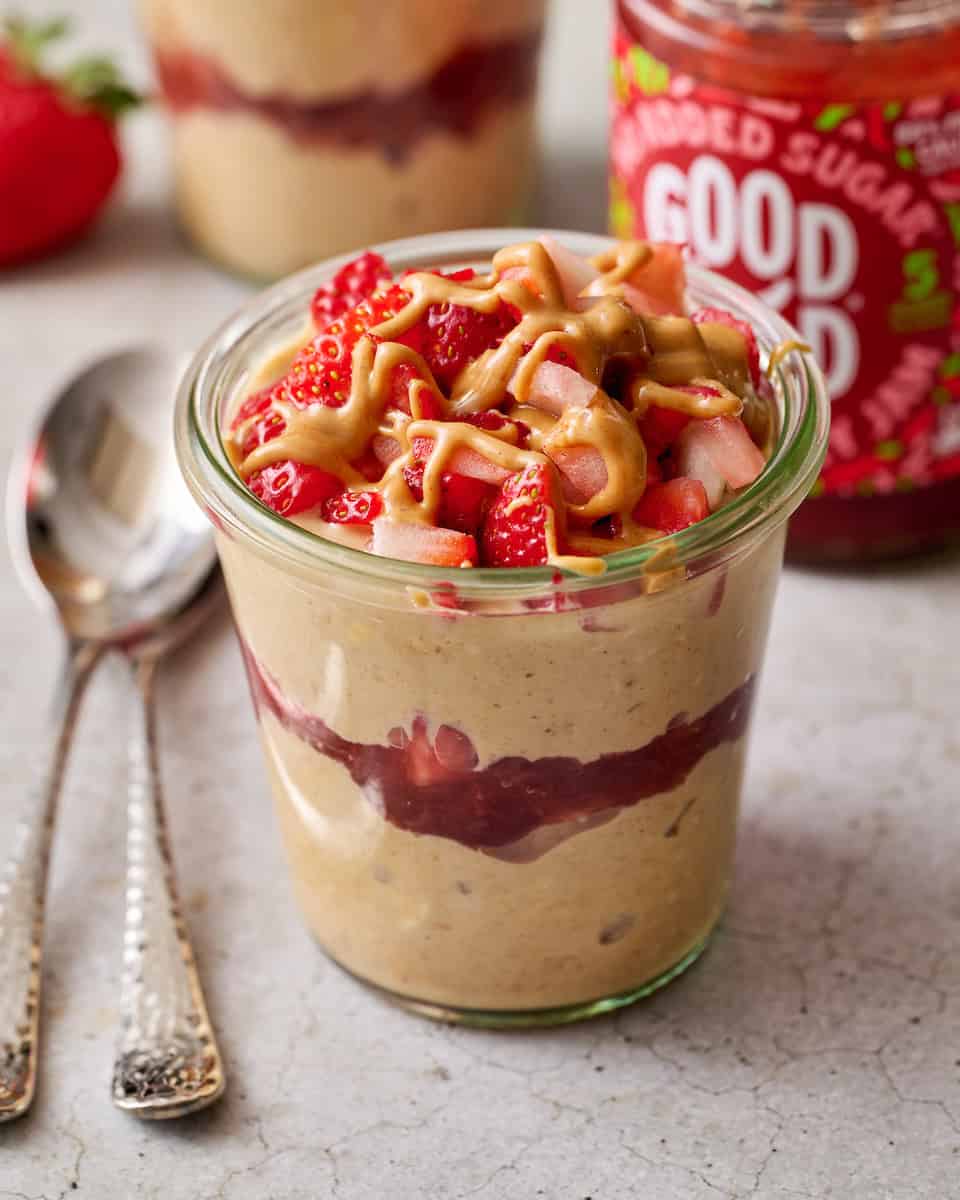 peanut butter and jelly overnight oats with protein topped with berries and peanut butter