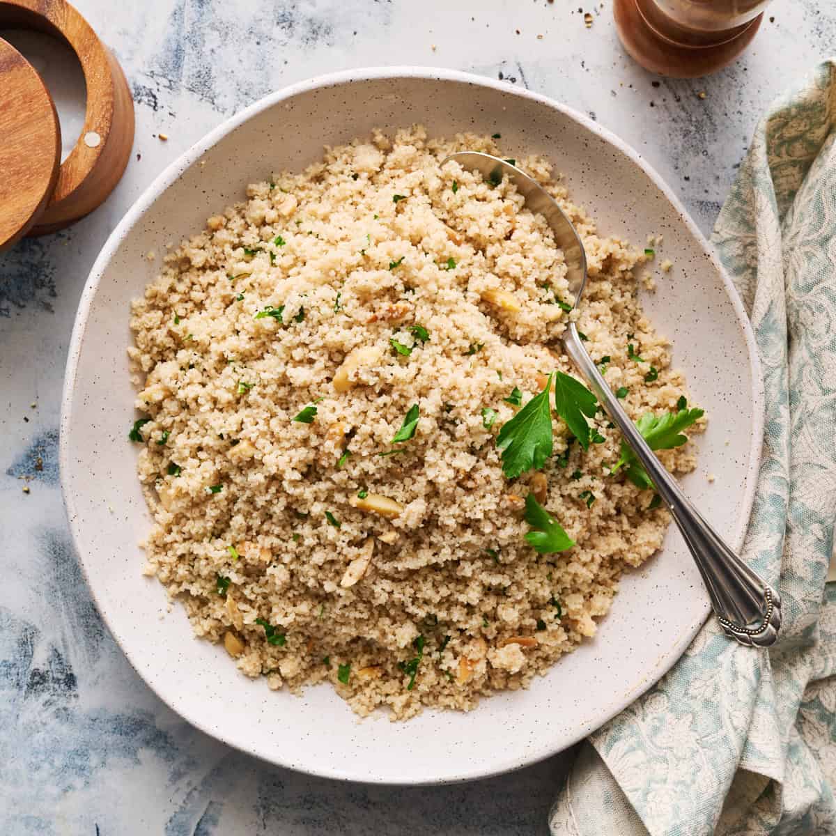 Fonio pilaf in a serving bowl garnished with herbs