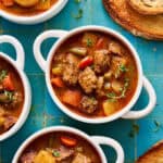 slow cooker beef stew in a white bowl with bread on the side