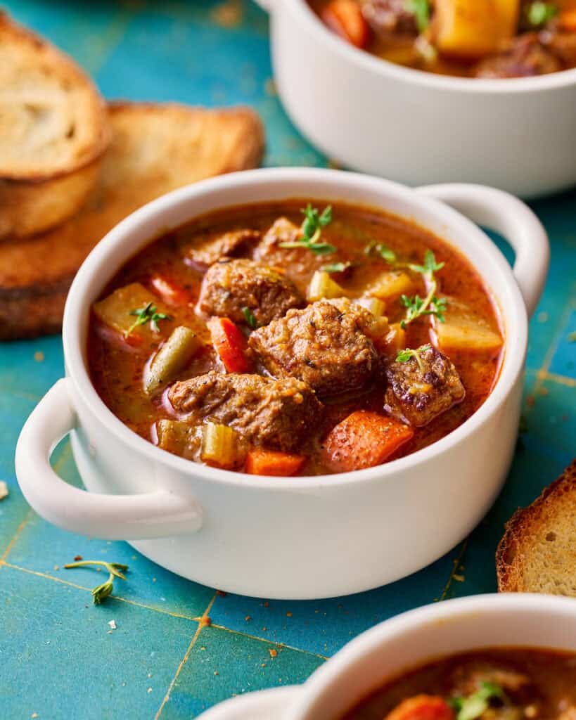 slow cooker beef stew with turnips instead of potatoes in a white bowl with bread on the side