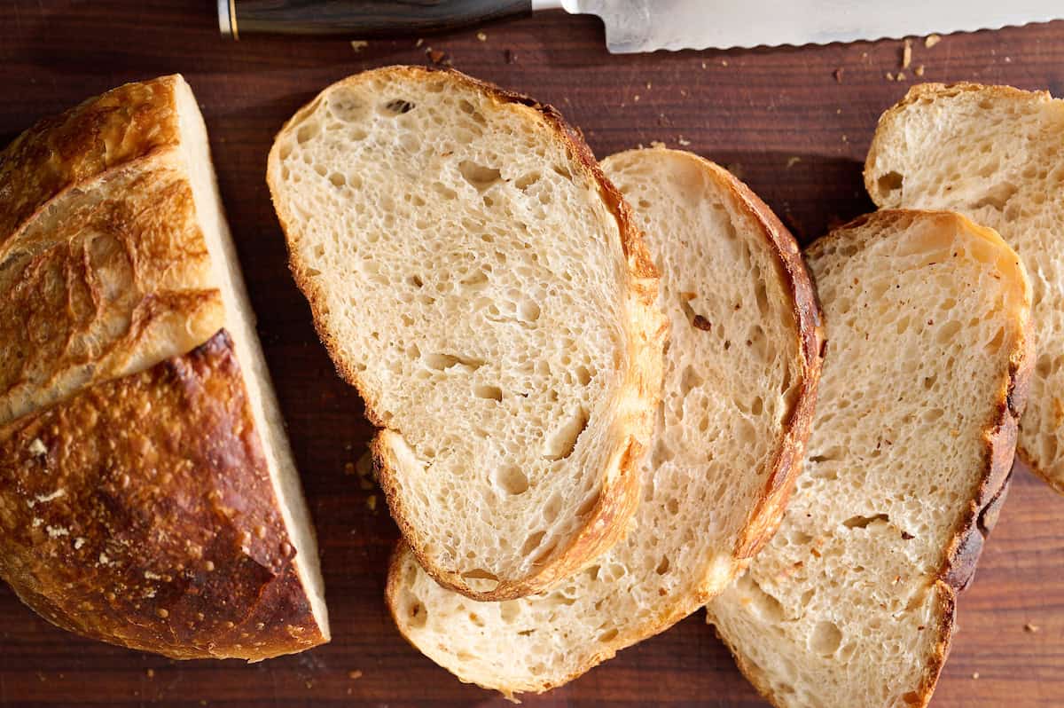 sliced sourdough bread with open crumb on a wooden cutting board