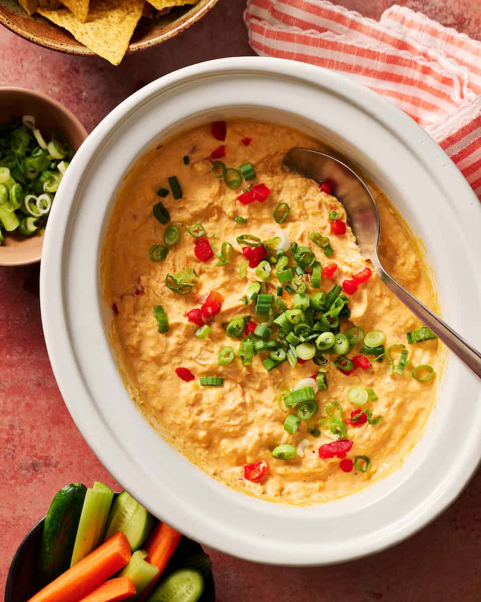 Creamy spicy buffalo chicken dip with chopped green onions and red peppers, perfect for snacks, parties.