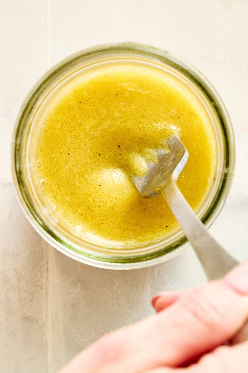 mixing up caesar dressing in a glass dressing jar
