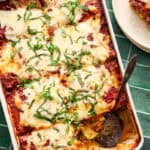 a pan of sliced zucchini lasagna topped with fresh basil
