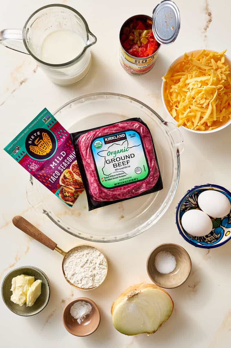 ingredients to make taco pie including ground beef, shredded cheese, eggs and taco seasoning