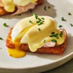 hash brown eggs benedict with a runny egg and topped with cottage cheese hollandaise and chives