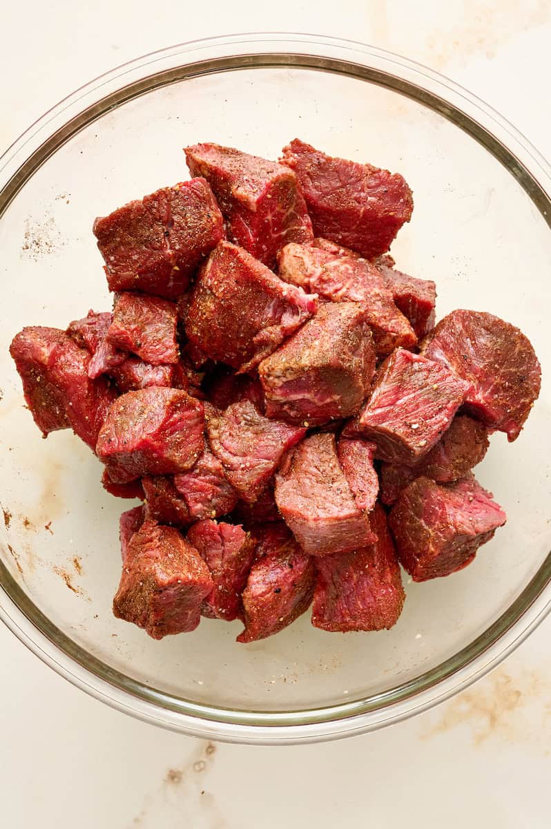 tossing the beef in cumin, salt, pepper and paprika