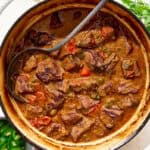 cast iron dutch oven with carne guisada and tortillas on the side