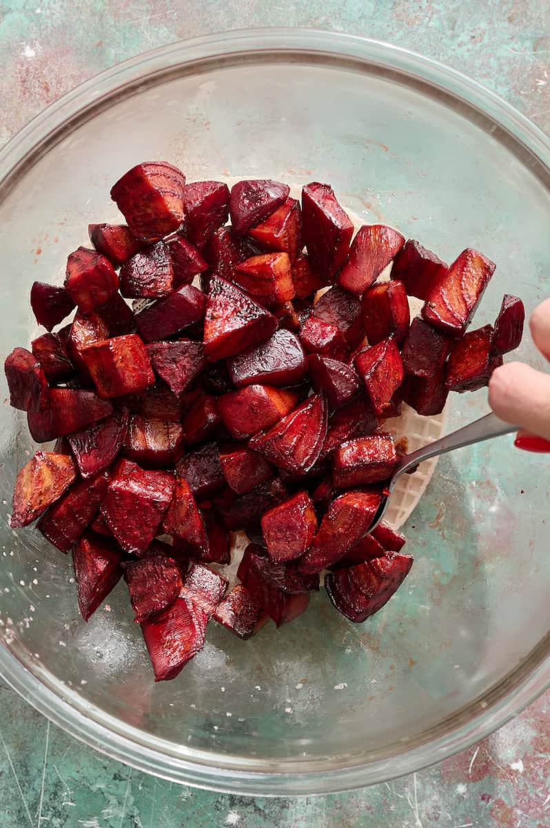roasted beets being tossed in vinegar