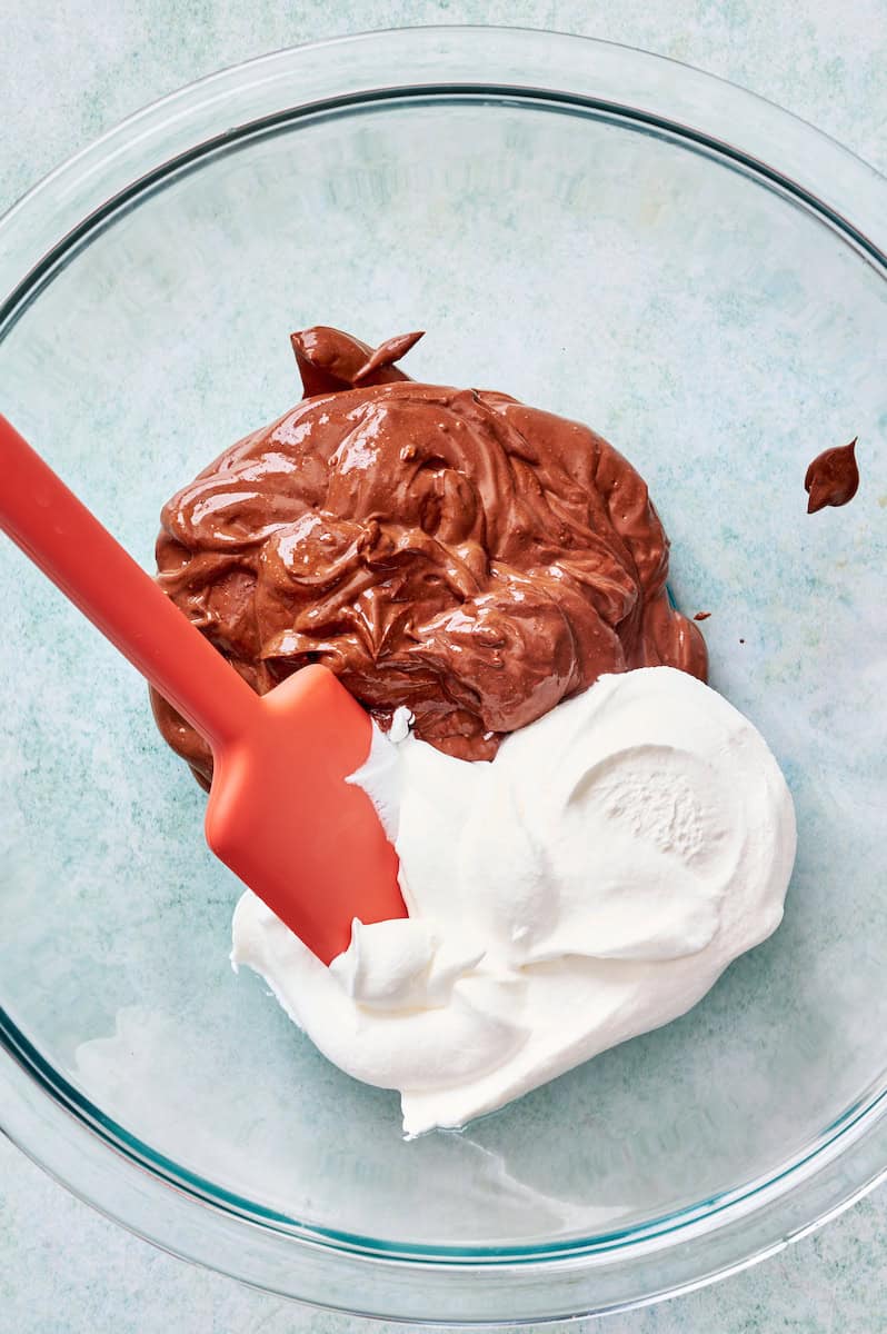 adding whipped cream to the bowl with the chocolate base